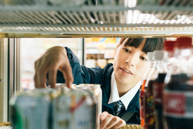 飲料の補充をする女性コンビニスタッフ